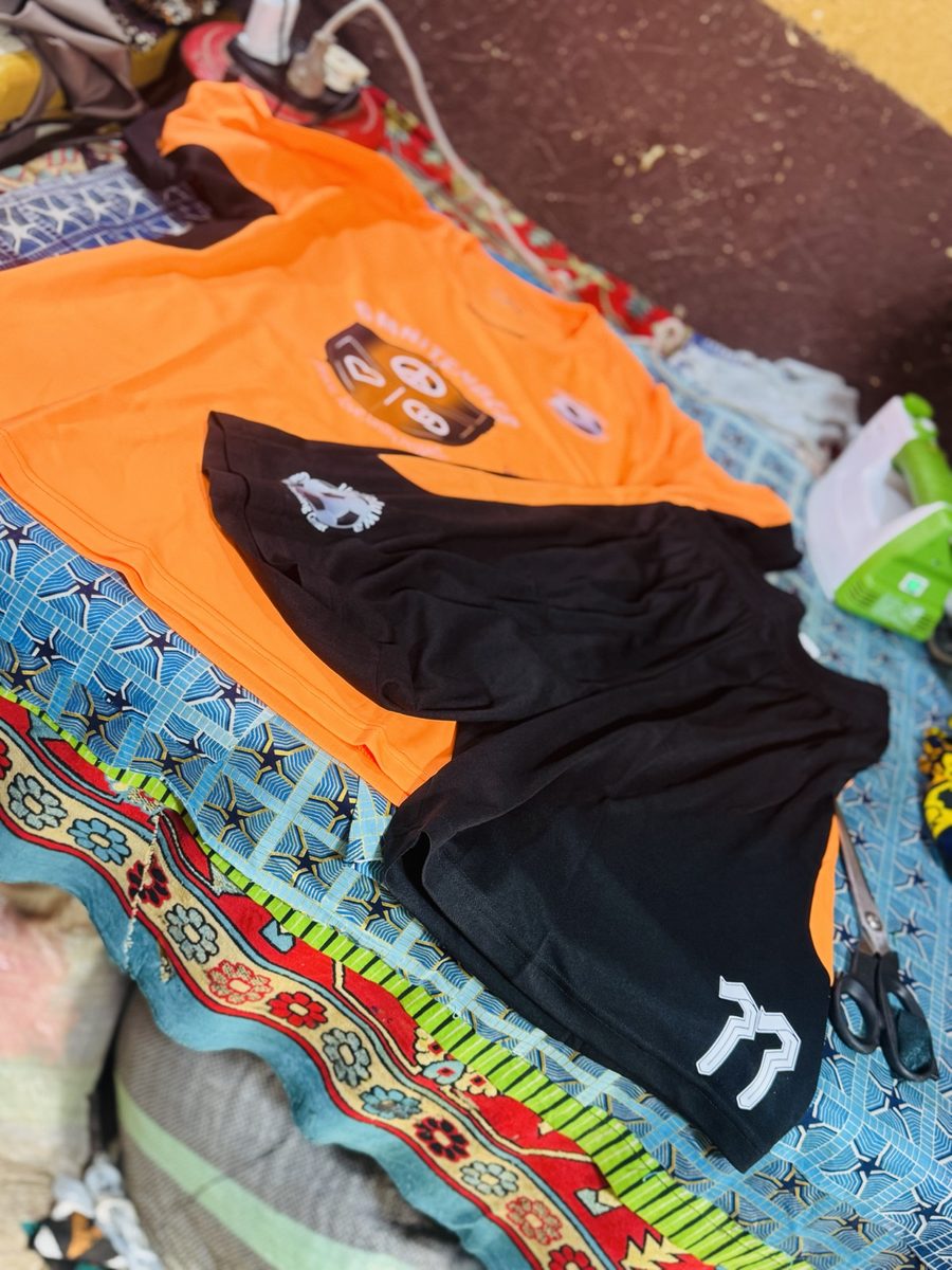 Orange goalkeeper jersey and black shorts laid out