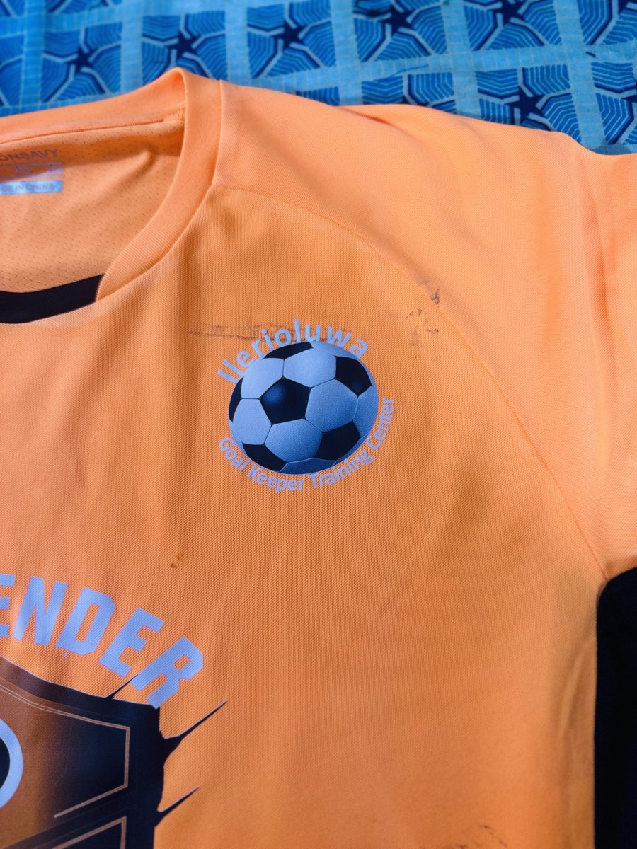 Ilerioluwa Goalkeeper Training Center crest on orange kit